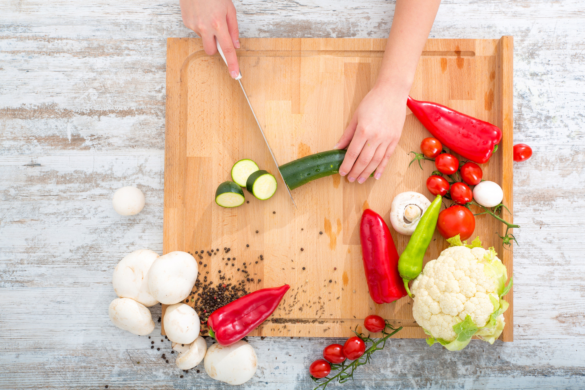 Hands chopping vegetables on a board